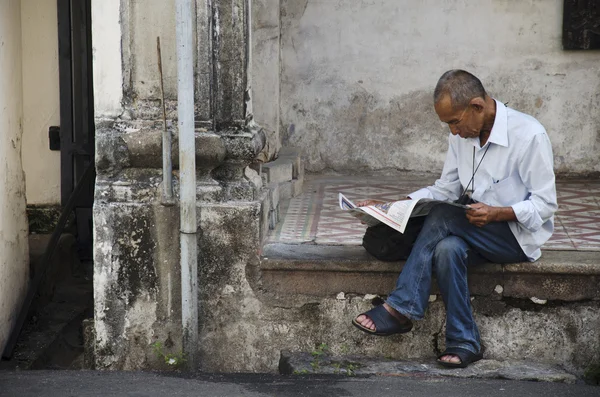 Malaysian old man reading newspaper at old building at Georgetow