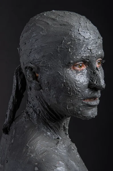 Statuesque woman in wet clay. Spa treatment.