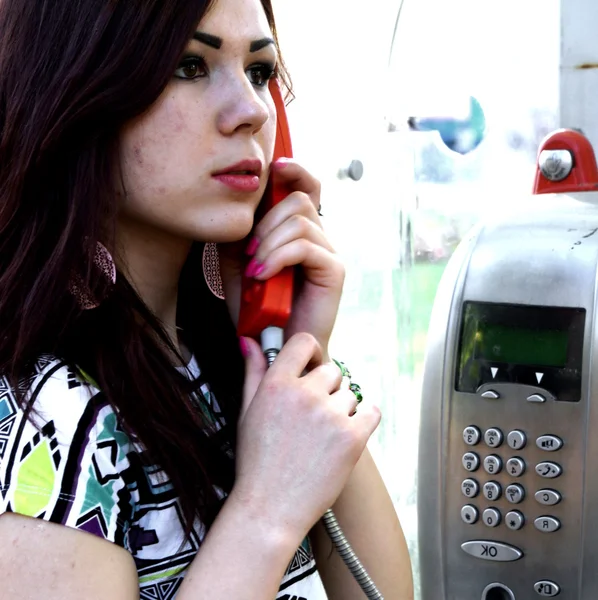Young woman talking on a pay phone