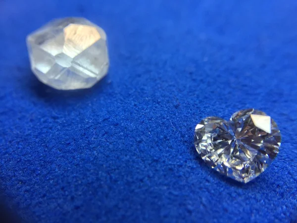 Rough diamond and diamond in the shape of a heart on a blue cloth