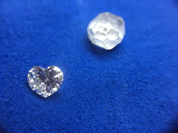 Rough diamond and diamond in the shape of a heart on a blue cloth