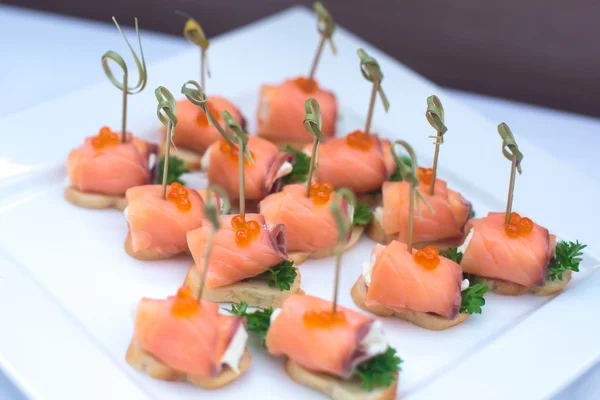 Beautifully decorated catering banquet table with different food snacks and appetizers with sandwich, caviar, fresh fruits on corporate christmas birthday party