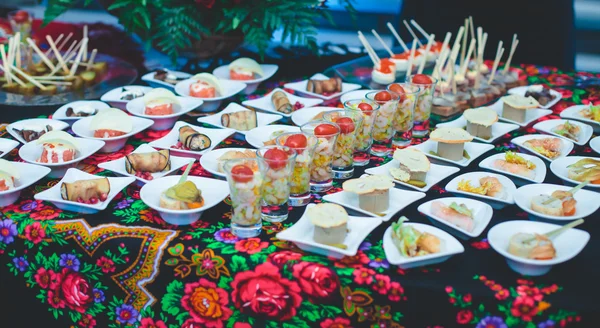 Beautifully decorated catering banquet table with different food snacks and appetizers with sandwich, caviar, fresh fruits on corporate christmas birthday party