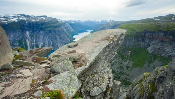 A vibrant picture of famous norwegian hiking place - trolltunga, the trolls tongue, rock skjegedall, with a tourist, and lake ringedalsvatnet and mountain panoramic scenery epic view, Norway