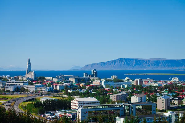 Beautiful super wide-angle aerial view of Reykjavik, Iceland with harbor and skyline mountains and scenery beyond the city, seen from the observation tower of Hallgrimskirkja Cathedral.