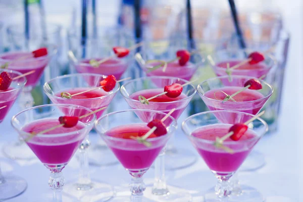 Beautiful line of different coloured cocktails with smoke on a open air party, tequila, martini, vodka, and others on decorated catering bouquet table on open air christmas party