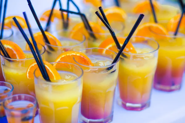 Beautiful line of different colored cocktails with smoke on a Christmas party, tequila, martini, vodka, and others on decorated catering bouquet table on open air party