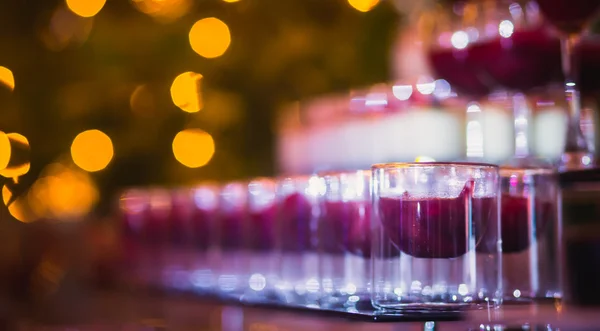 Beautiful line of different colored cocktails with smoke on a Christmas party, tequila, martini, vodka, and others on decorated catering bouquet table on open air party