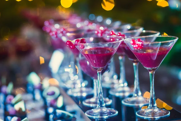 Beautiful line of different colored cocktails with smoke on a Christmas party, tequila, martini, vodka, and others on decorated catering bouquet table on open air party