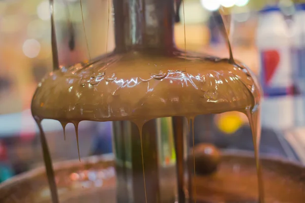 Vibrant Picture of Chocolate Fountain Fontain on childen kids birthday party with a kids playing around and marshmallows and fruits dip dipping into fountain