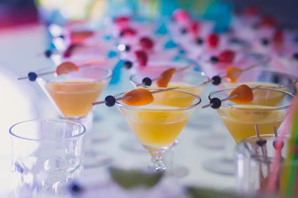 Beautiful row line of different colored alcohol cocktails with mint on a christmas party, martini, vodka,and others on decorated catering bouquet table on open air event
