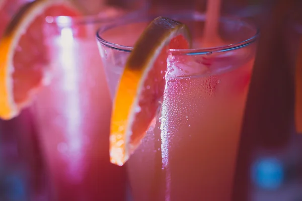 Beautiful row line of different colored alcohol cocktails with mint on a christmas party, martini, vodka,and others on decorated catering bouquet table on open air event