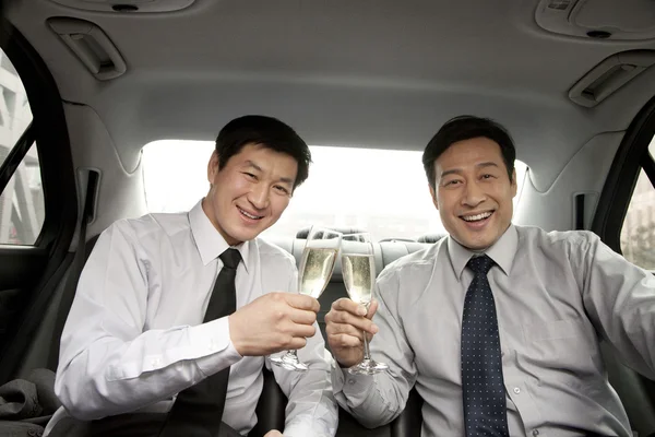 Businessmen toasting in back of car