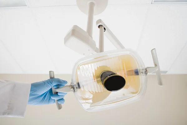 Dentist with lamp in operating theatre