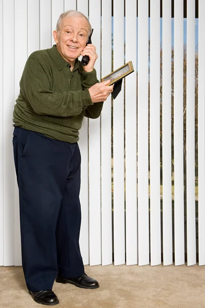 Man talking on telephone and holding picture frame