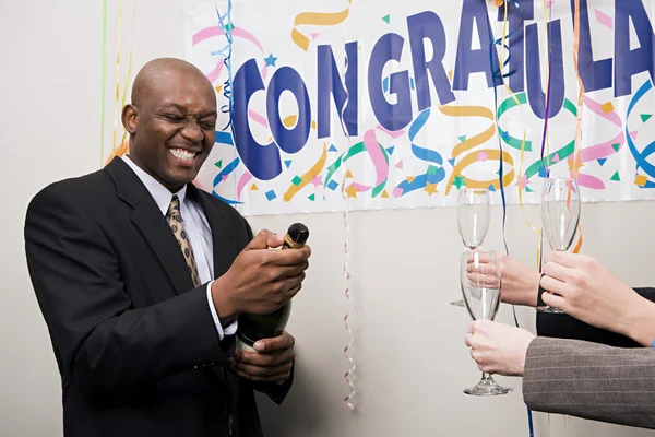 Businessman opening a bottle of champagne