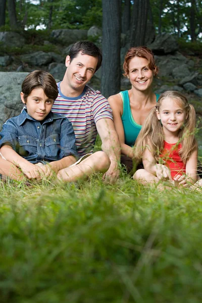 Family in forest sitting on grass