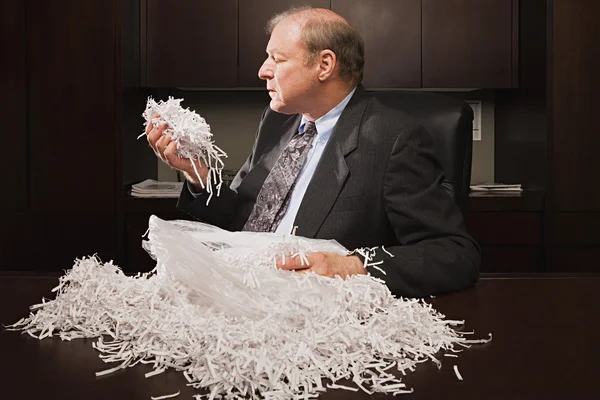 Mature businessman playing with paper shreddings