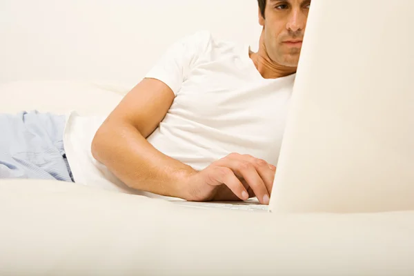 Man on bed using laptop computer