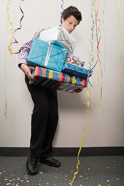 Businessman struggling with pile of presents