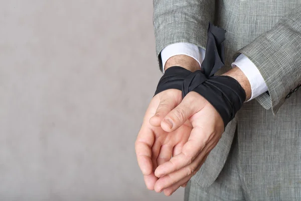 Man\'s tied hands with black fabric