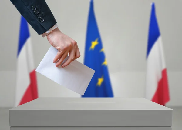 Election in France. Voter holds envelope in hand above vote ballot.