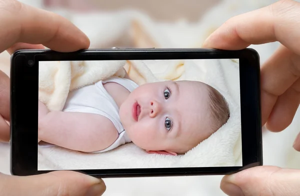 Parent is taking photo of a baby with smartphone.