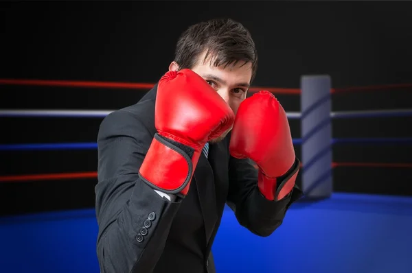 Businessman is fighting and hiding his face in ring.