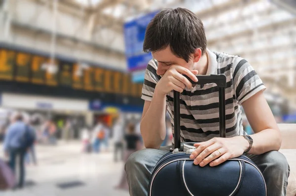 Delayed train concept. Tired passenger is waiting for train arrival in train station.