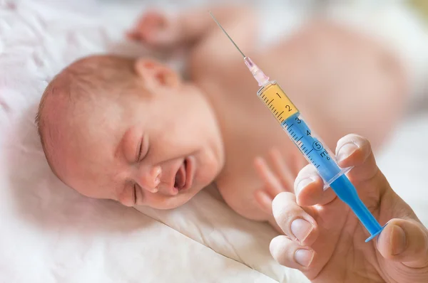 Doctor holds syringe to vaccinate sick baby with injection