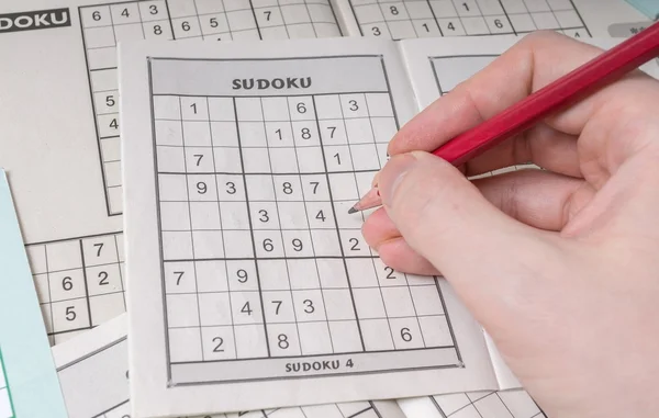 Hand is solving sudoku crossword, popular puzzle game.