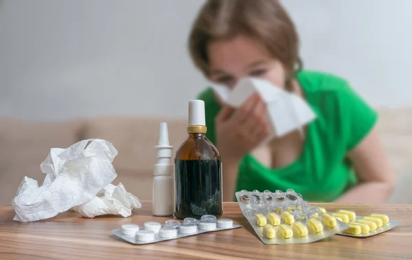Pills in front of ill woman who has flu or cold.