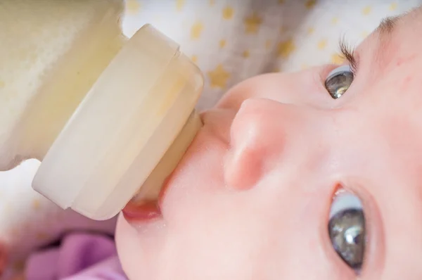 Close up view on feeding little baby with milk formula in bottle