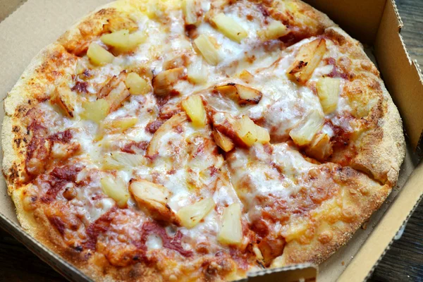 Whole Hawaiian pizza with pineapple and chicken in delivery box