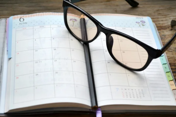 An empty retro daily planner with black pencil and reading glasses