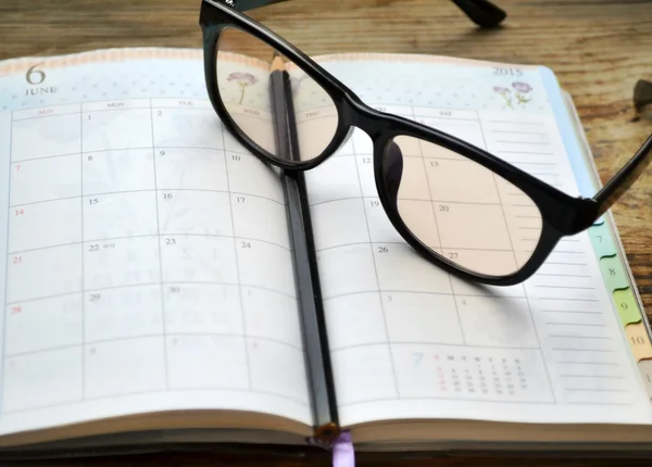 An empty retro daily planner with black pencil and reading glasses