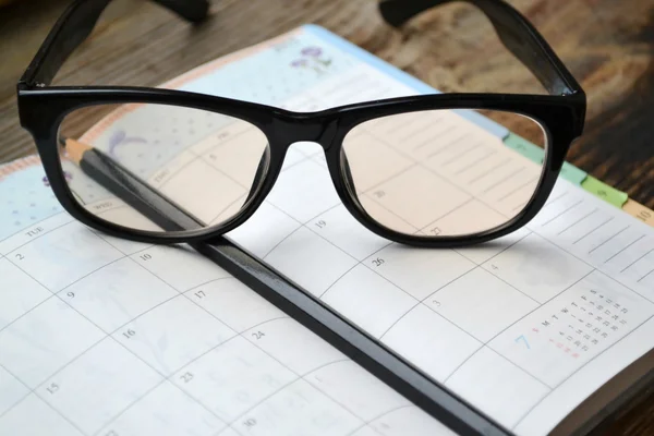 An empty retro daily planner with black pencil and reading glasses