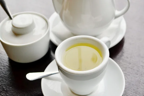 White tea set with a cup of herbal tea