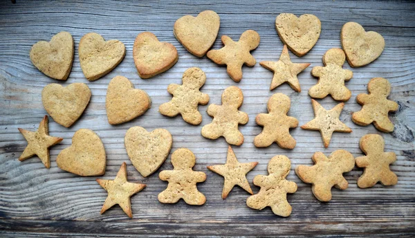 Gingerbread cookies in shapes of heart, star and man on wooden table