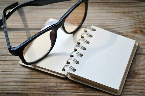 An empty retro spiral notebook with old paper and reading glasses