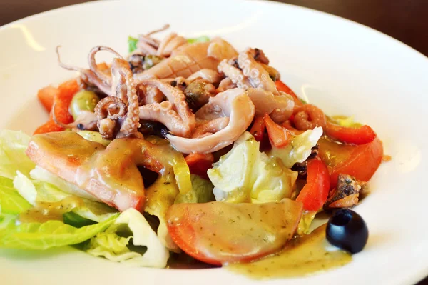 Big plate with seafood salad with olives and squid