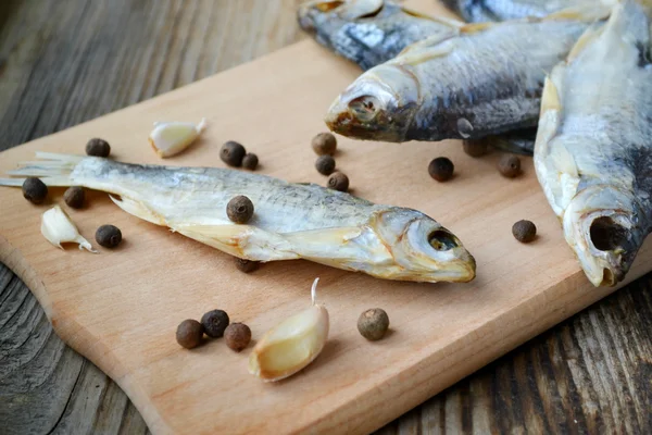 Salty stockfish cod on wooden board with gaarlic and pepper