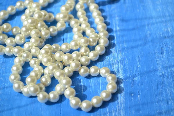 A pearl necklace on blue wooden table