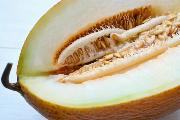 Tasty orange melon cut in half on white wooden board
