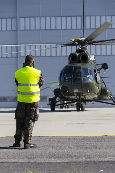Man in military uniform stands in front of polish Mi-8T helicopter during airshow session NATO Days