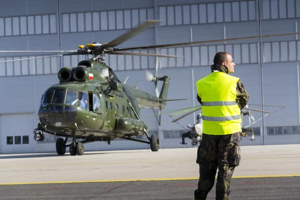 Man in military uniform stands in front of polish Mi-8T helicopter during airshow session NATO Days