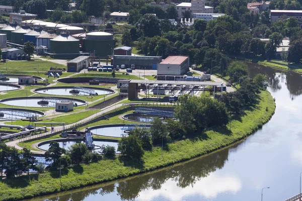 Aerial view of river meandering around sewage water treatment plant