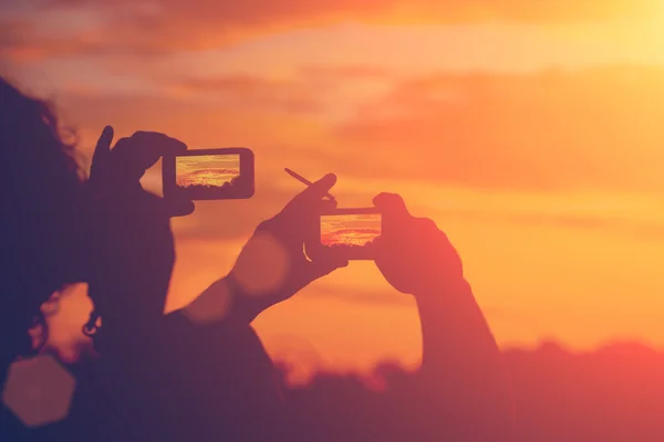 Silhouettes of people taking pictures of sunset