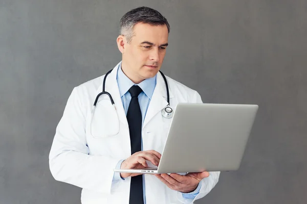 Mature male doctor with laptop