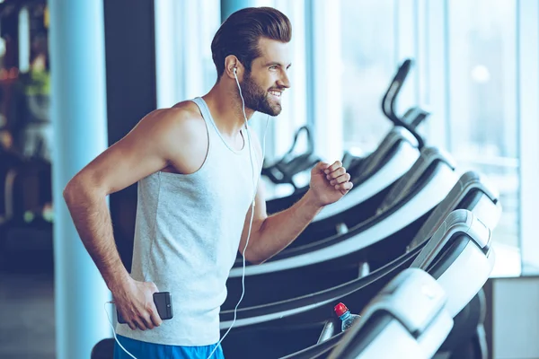 Handsome man with headphones on treadmill